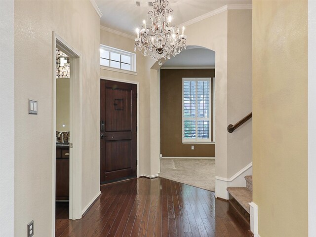 entryway featuring crown molding, arched walkways, baseboards, and dark wood-style floors