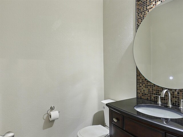 bathroom with backsplash, toilet, and vanity