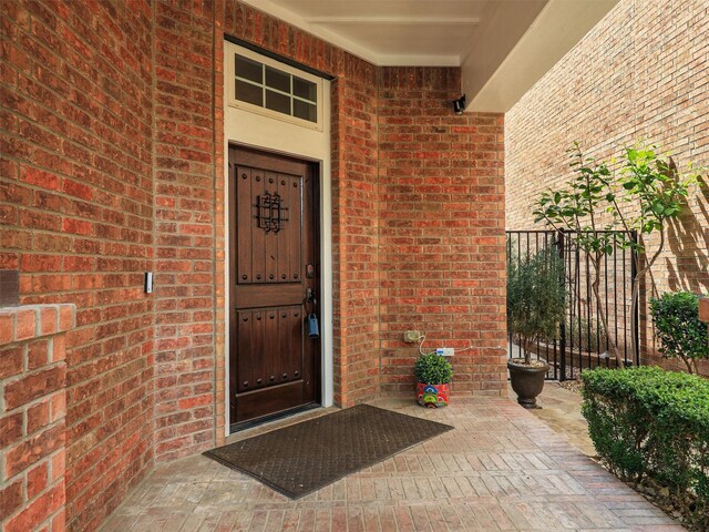 doorway to property with fence and brick siding