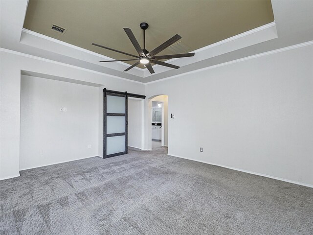 empty room with visible vents, arched walkways, ceiling fan, and a tray ceiling