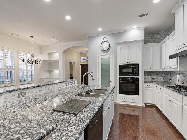 kitchen featuring backsplash, arched walkways, dark wood finished floors, a sink, and black appliances