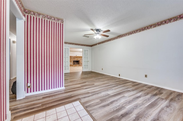 1515 Senter Rd, Irving, TX 75060 - unfurnished living room featuring a ceiling fan, a textured ceiling, a fireplace, wood finished floors, and baseboards