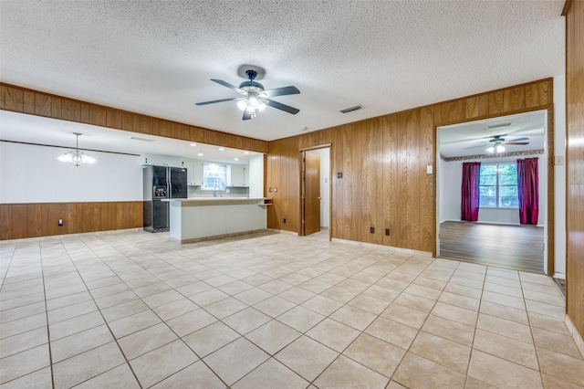 1515 Senter Rd, Irving, TX 75060 - unfurnished living room with wooden walls, a textured ceiling, visible vents, and ceiling fan with notable chandelier