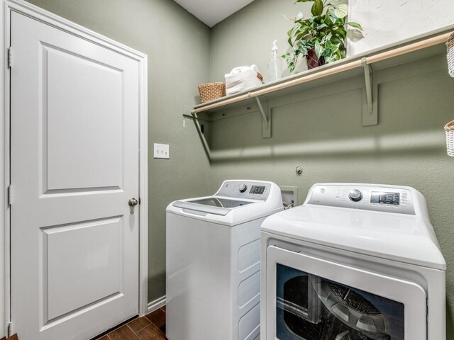 laundry area with baseboards, laundry area, dark wood-style floors, and washer and clothes dryer