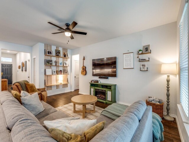living room featuring baseboards, ceiling fan, and wood finished floors