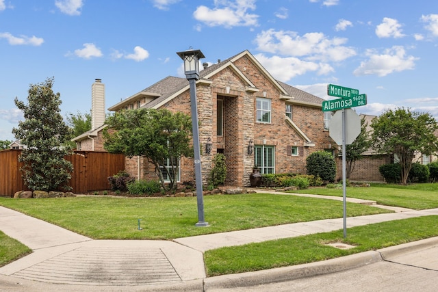 view of front of property featuring brick siding, fence, and a front lawn
