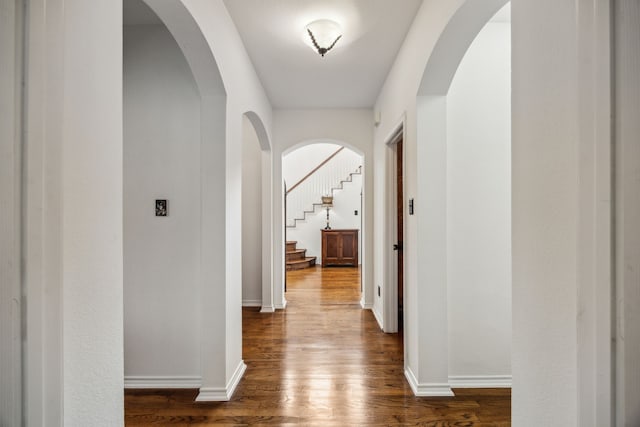 hall featuring baseboards, stairway, and dark wood-type flooring