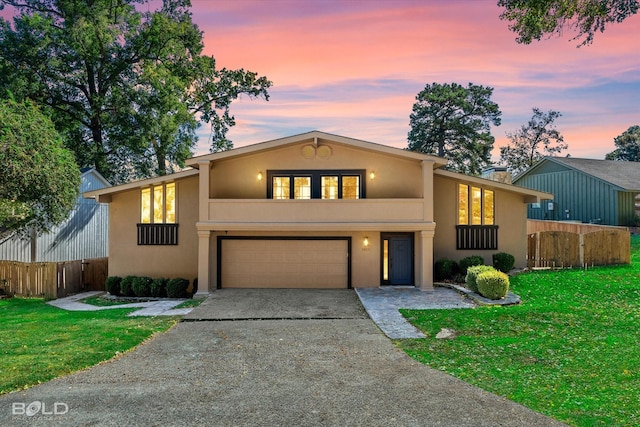 view of front of house with fence, aphalt driveway, a front yard, and stucco siding