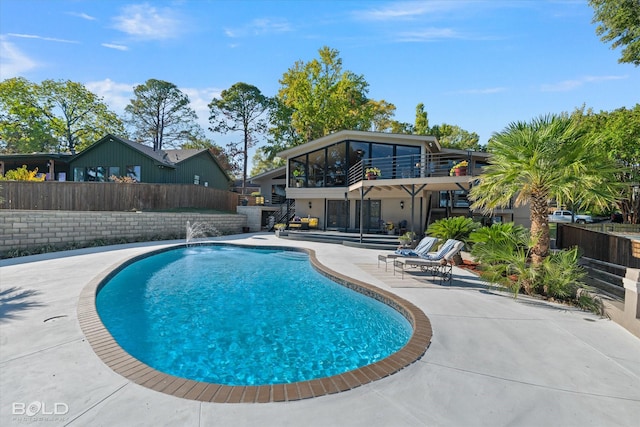 view of swimming pool featuring a fenced backyard, a fenced in pool, a patio, and a sunroom