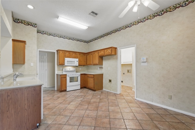 kitchen featuring brown cabinets, a sink, white appliances, a ceiling fan, and visible vents