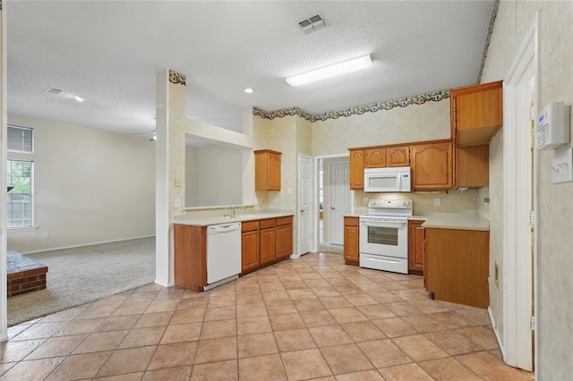 kitchen featuring visible vents, light countertops, brown cabinetry, and white appliances
