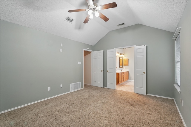 unfurnished bedroom featuring visible vents, lofted ceiling, and light colored carpet