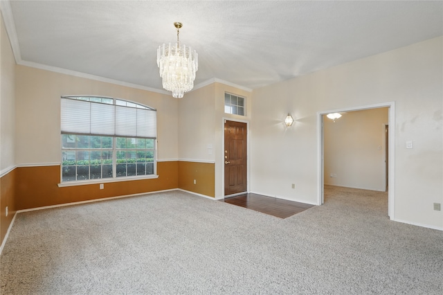carpeted empty room with crown molding, baseboards, and a notable chandelier
