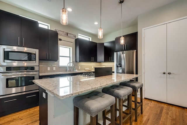 kitchen featuring appliances with stainless steel finishes, dark cabinetry, a center island, and a kitchen breakfast bar