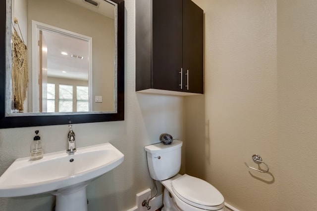 bathroom with a sink, toilet, and visible vents