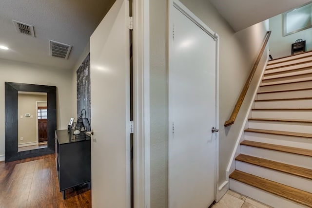 stairs featuring visible vents, baseboards, and wood finished floors