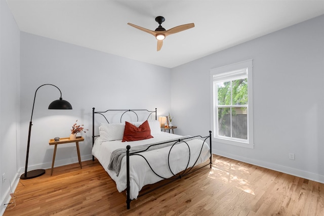 bedroom featuring baseboards, a ceiling fan, and light wood-style flooring