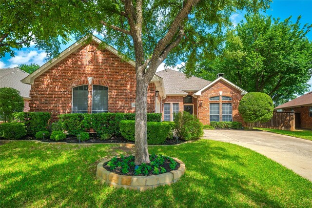 view of front of home featuring roof with shingles, a front lawn, and brick siding