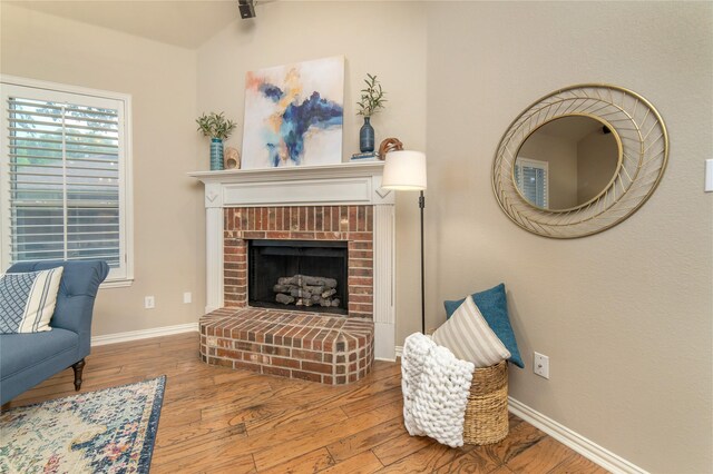 living area with baseboards, a fireplace, and hardwood / wood-style floors