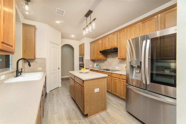 kitchen with a sink, arched walkways, under cabinet range hood, visible vents, and black appliances