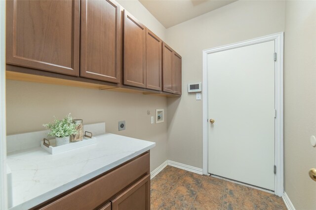 clothes washing area featuring baseboards, cabinet space, electric dryer hookup, stone finish flooring, and washer hookup