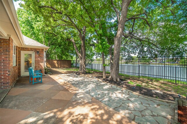 view of patio / terrace featuring a water view and a fenced backyard
