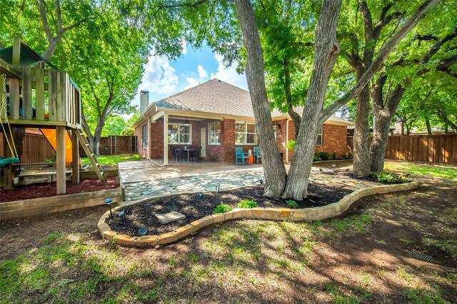 back of property featuring a chimney, roof with shingles, brick siding, a fenced backyard, and a patio