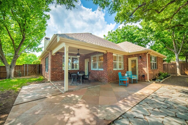 rear view of property with a fenced backyard, a patio, ceiling fan, and brick siding