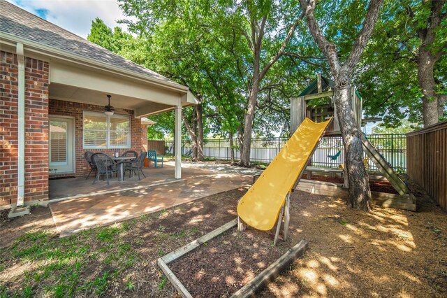 view of jungle gym featuring fence, a ceiling fan, and a patio area