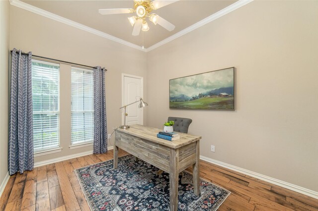 office space featuring crown molding, baseboards, a ceiling fan, and light wood-style flooring