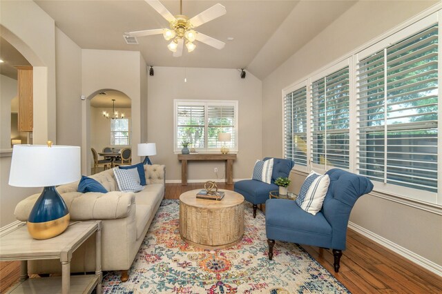 living room with arched walkways, ceiling fan with notable chandelier, baseboards, wood finished floors, and visible vents