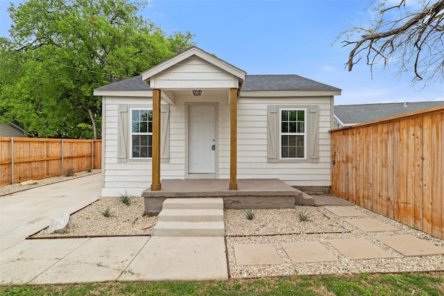 bungalow-style home featuring roof with shingles and a fenced backyard