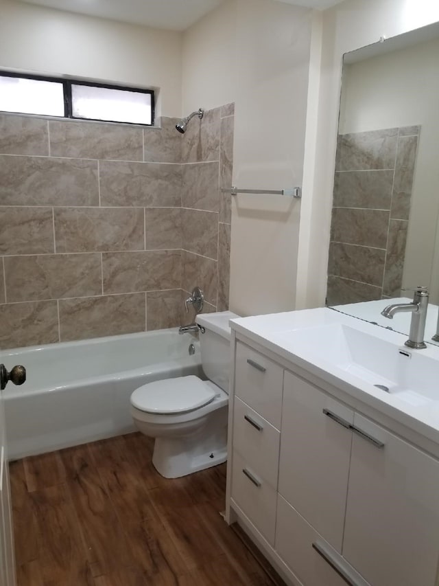 full bath with toilet,  shower combination, wood finished floors, and vanity