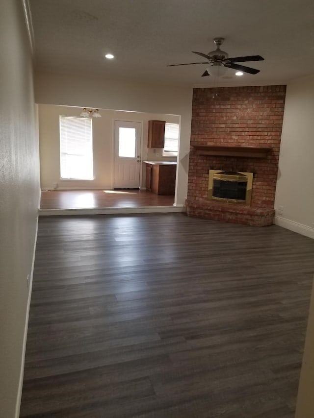 unfurnished living room with recessed lighting, baseboards, a fireplace, and dark wood-style flooring