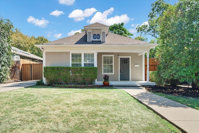 view of front of house featuring a porch, fence, roof with shingles, and a front lawn