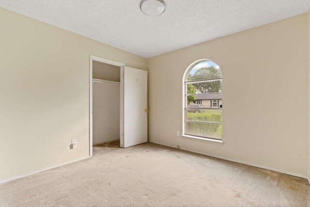unfurnished bedroom featuring carpet, a closet, and a textured ceiling