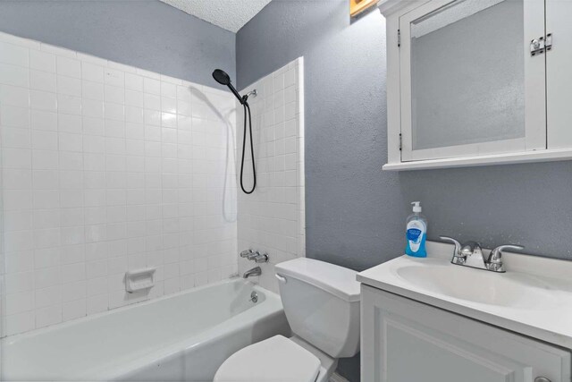 bathroom with vanity, a textured wall, washtub / shower combination, and toilet