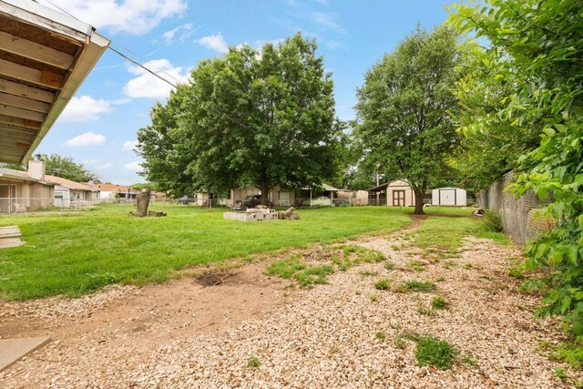 view of yard with fence, an outbuilding, and a shed