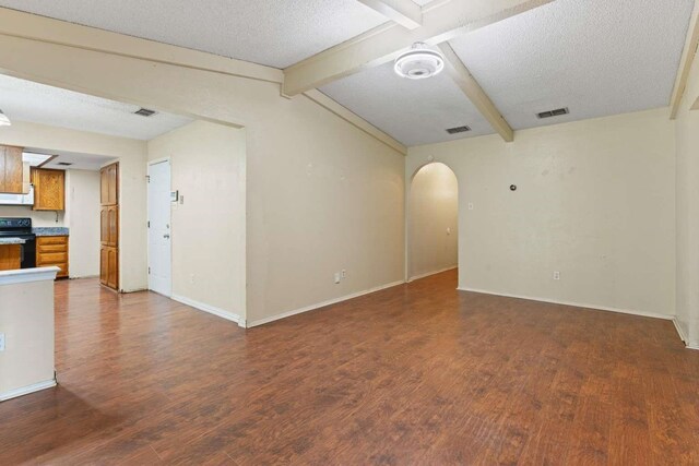 empty room featuring dark wood-style flooring, arched walkways, visible vents, and baseboards