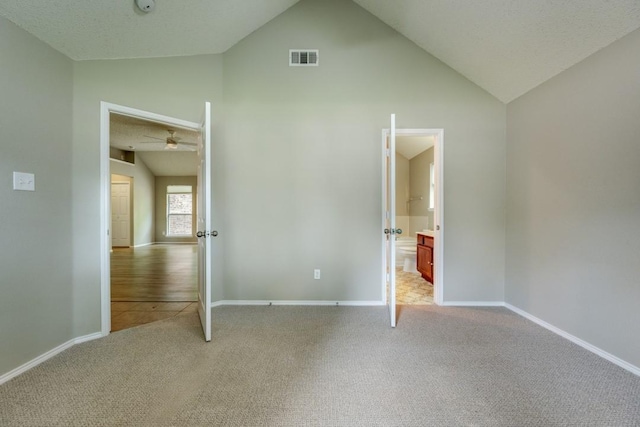 unfurnished bedroom featuring visible vents, baseboards, high vaulted ceiling, and light carpet