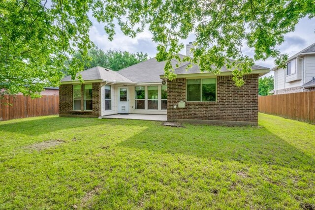 rear view of house featuring a fenced backyard, a patio area, and brick siding