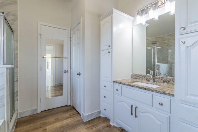 full bath with vanity, a stall shower, and wood finished floors