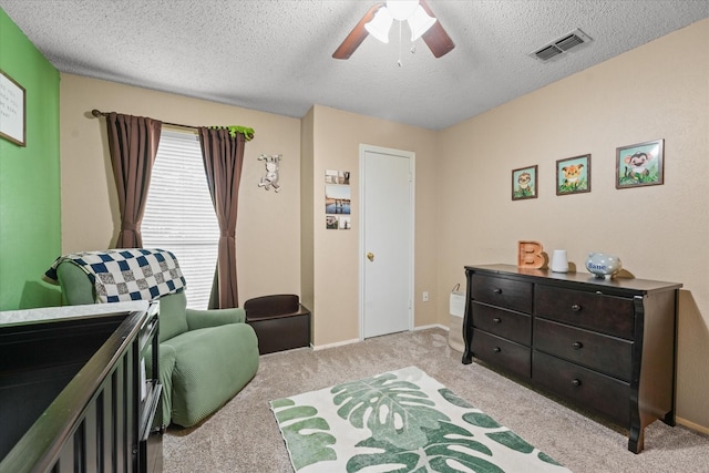 bedroom with visible vents, light carpet, baseboards, ceiling fan, and a textured ceiling
