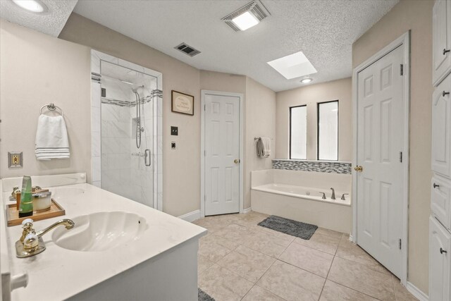 bathroom with a sink, a skylight, visible vents, a bath, and a stall shower