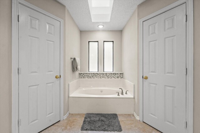 full bath featuring a textured ceiling, a skylight, tile patterned floors, and a bath