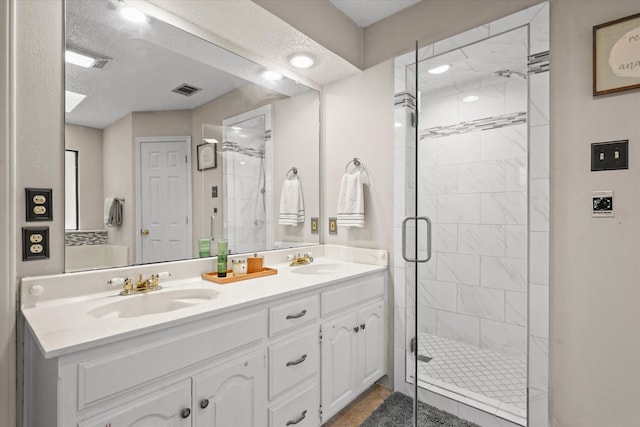 bathroom with double vanity, a shower stall, and a sink