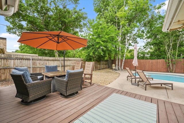 deck featuring outdoor dining area, a fenced backyard, and a fenced in pool