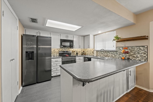 kitchen featuring a sink, a peninsula, backsplash, visible vents, and black appliances