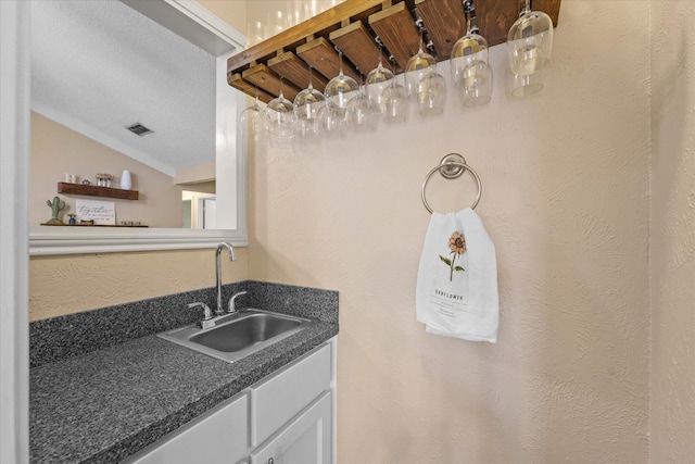 bar featuring visible vents, a sink, and indoor wet bar