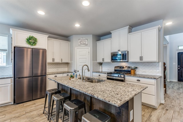 kitchen featuring a sink, light wood finished floors, appliances with stainless steel finishes, and white cabinets
